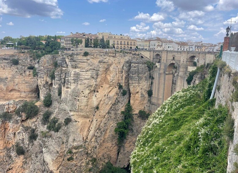 A cliffside with a historic building complex and a bridge. 3