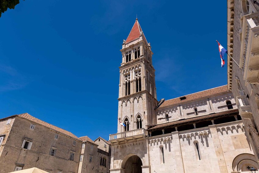 A historic building with a prominent tower, arches, and a flag. 4