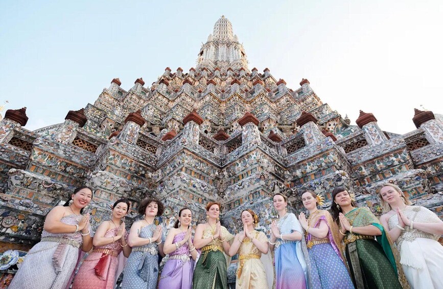 A group of people in traditional attire standing in front of a detailed, ornate temple structure. 1