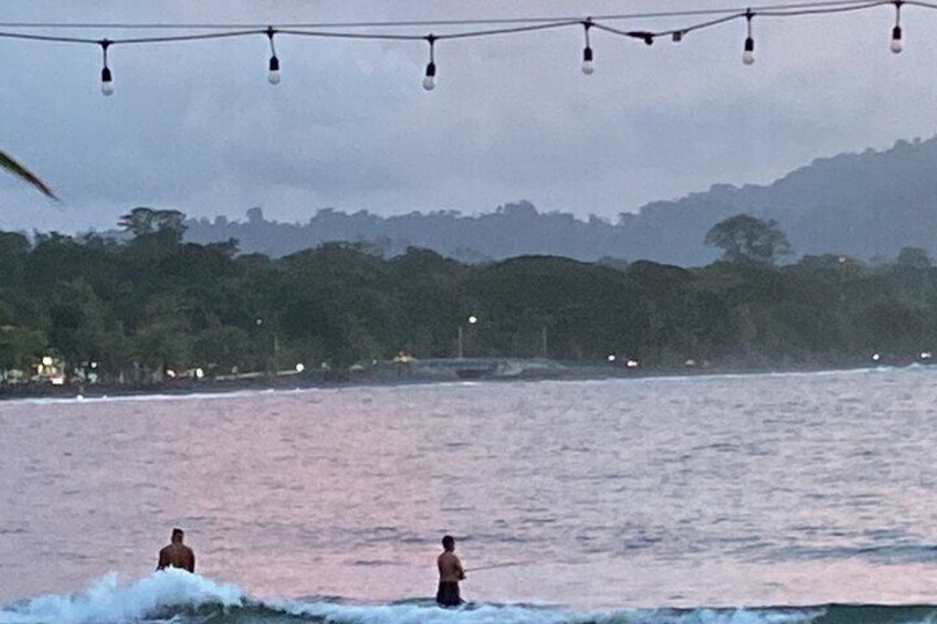 A beach with waves and a string of lights above. 2