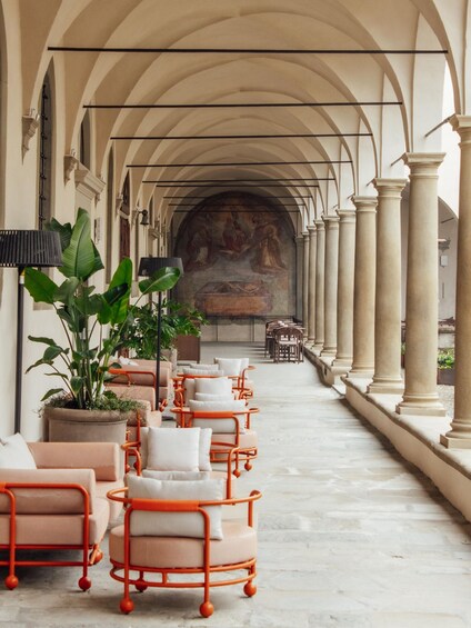 A corridor with arches, columns, and a mural on the wall. 5