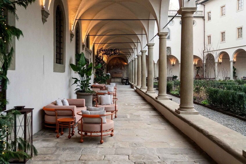 A covered outdoor seating area with chairs and tables, columns, and a stone pathway. 4