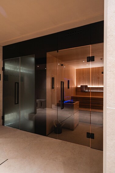 A modern interior with a glass partition, wooden paneling, and a blue-lit seating area. 3