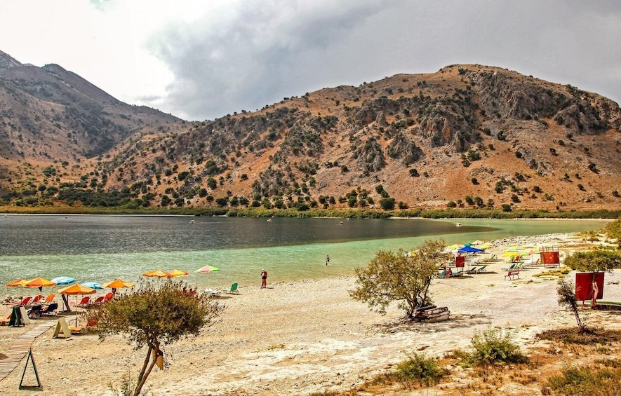 A beach with clear water, umbrellas, and a mountainous backdrop. 2