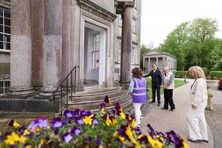 A historic building with columns and a person in a purple vest standing by the entrance. 5