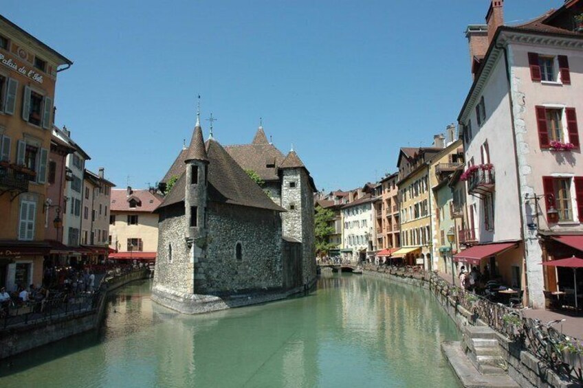 A historic stone building with a tower, a canal, and colorful buildings along the water's edge. 2