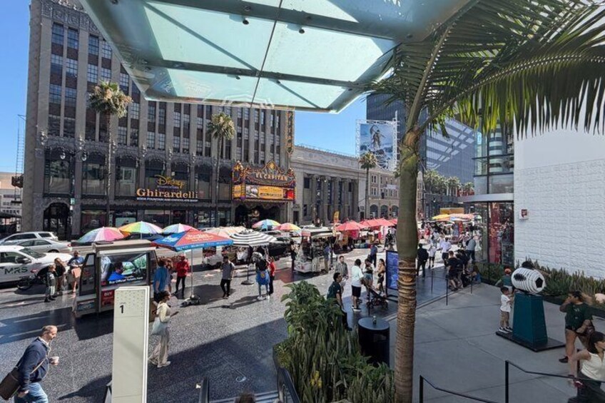 A busy outdoor market with food stalls and people walking. 4