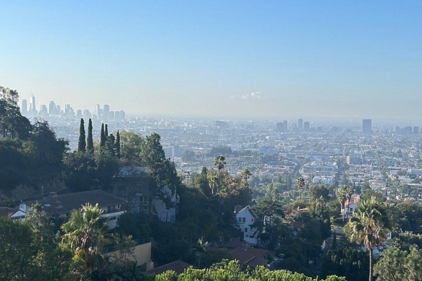 A cityscape with a prominent hill, dense greenery, and a distant skyline. 3