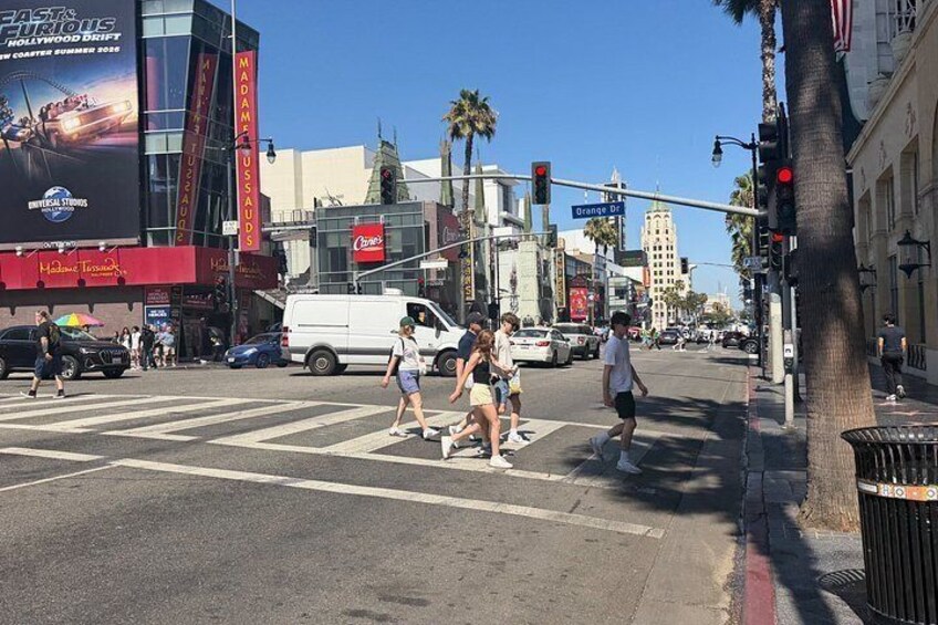 A busy intersection with pedestrians crossing, traffic lights, and commercial buildings. 3
