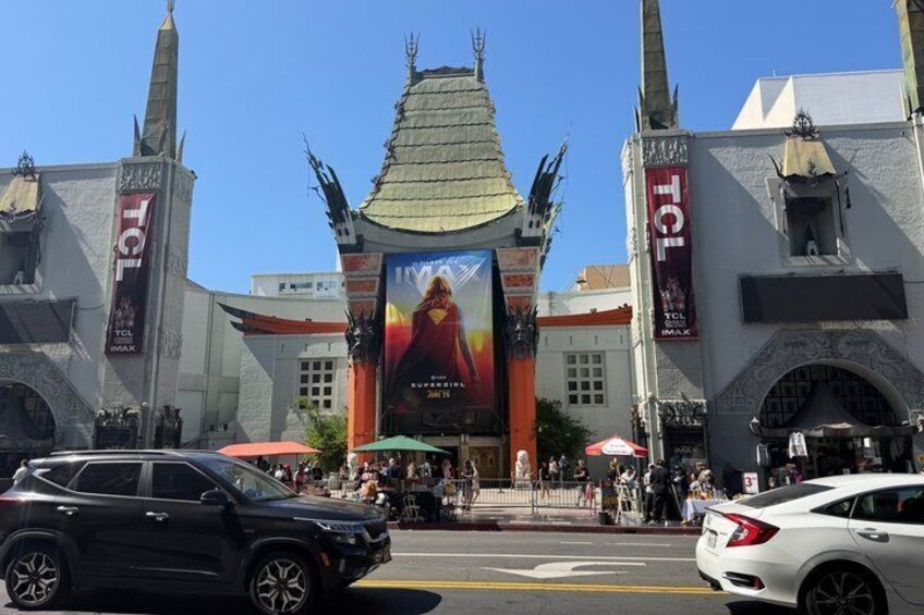 A building with a large banner, two towers, and a street with cars. 1