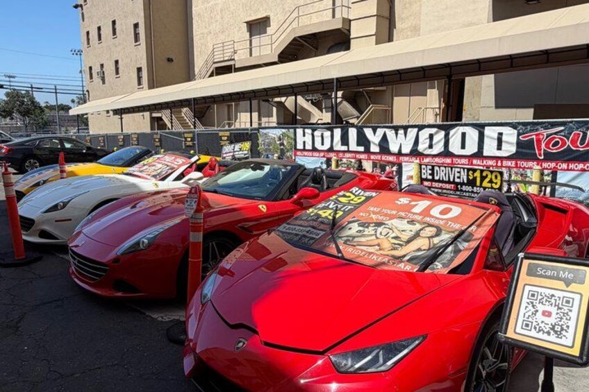 A red sports car parked in front of a building with a sign that reads 'HOLLYWOOD Tour.' 5