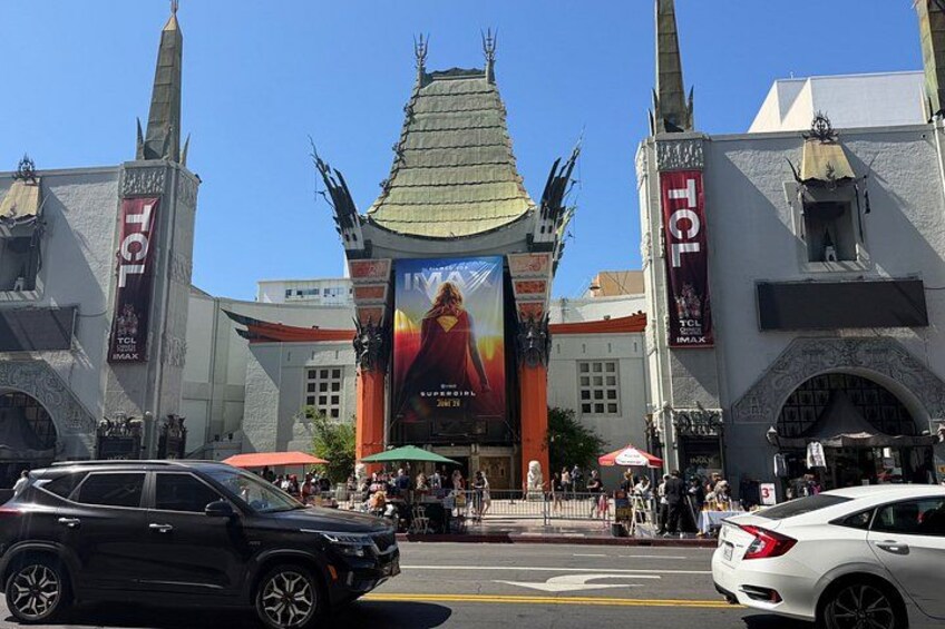 A building with a large banner, two towers, and a car in the foreground. 1