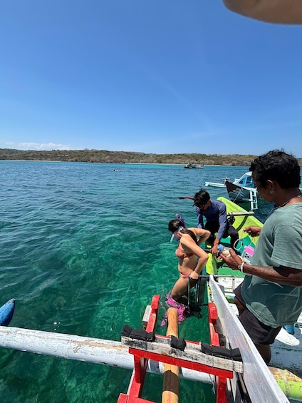 A group of people on a boat with clear blue water and a distant shoreline. 3