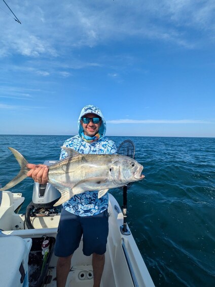 A person on a boat holding a large fish. 1