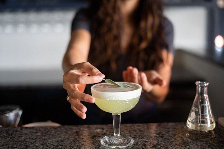 A person holding a cocktail glass with a lime wedge on a bar counter. 4