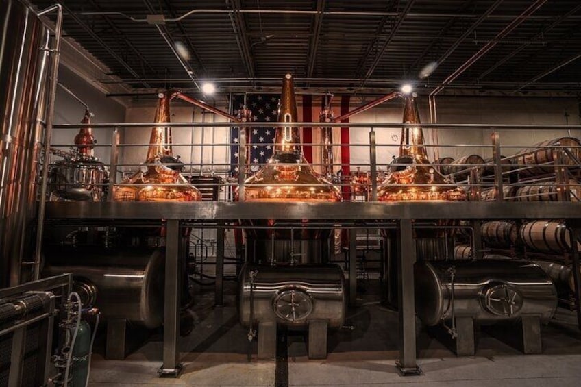 A distillery with copper stills, barrels, and a flag. 2