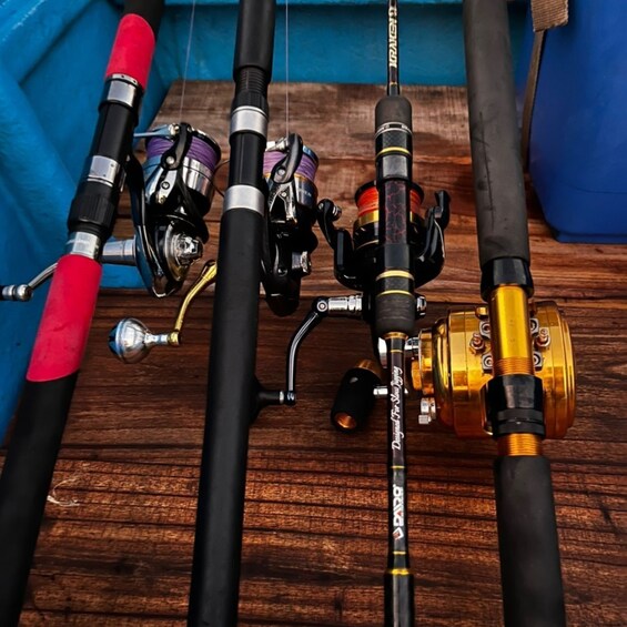 A collection of fishing rods and reels on a wooden surface. 3