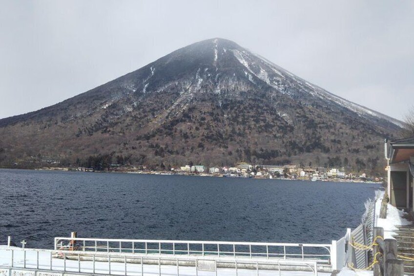 A snow-capped mountain, a body of water, and a distant shoreline with buildings. 4