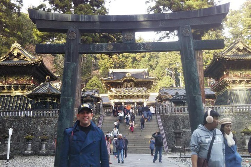 A traditional Japanese torii gate leading to a temple complex with visitors. 3