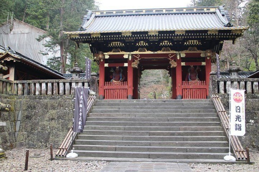 A traditional Japanese temple with a red torii gate, stone steps, and a sign with Japanese characters. 5