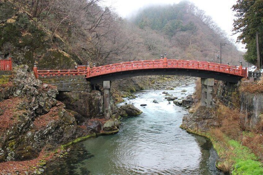 A red bridge over a river, surrounded by rocky terrain and trees. 2