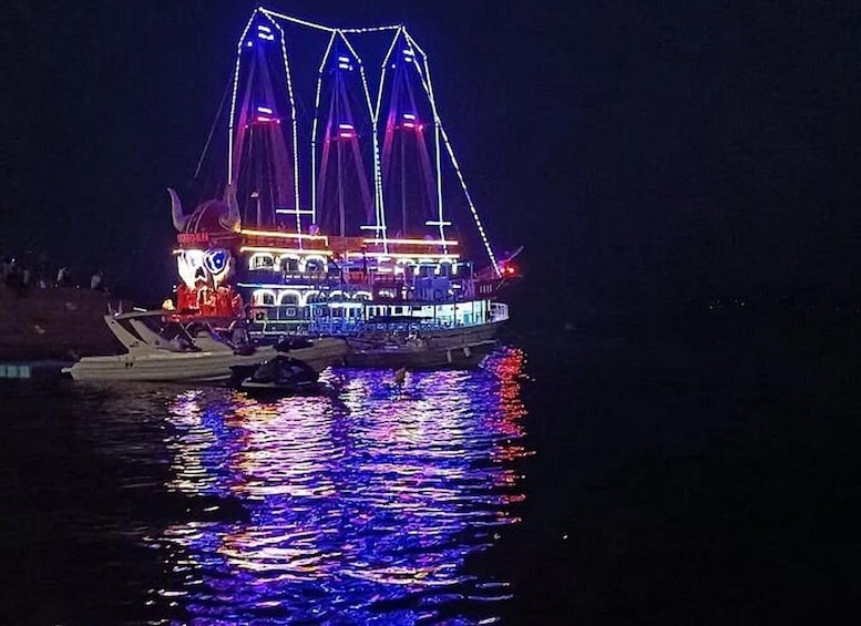 A brightly lit boat with a large sail, docked at night. 2