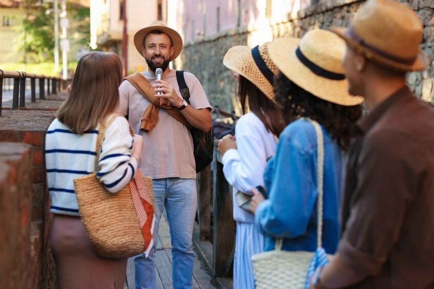 Un gruppo di persone su un sentiero di pietra, alcune con cappelli e una persona che tiene un microfono. 5