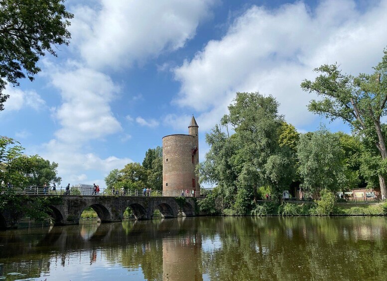 A historic tower, a stone bridge, and a calm river reflecting the sky. 5