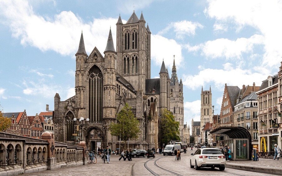 A historic cathedral with pointed spires and a clock tower, surrounded by cobblestone streets and traditional buildings. 2