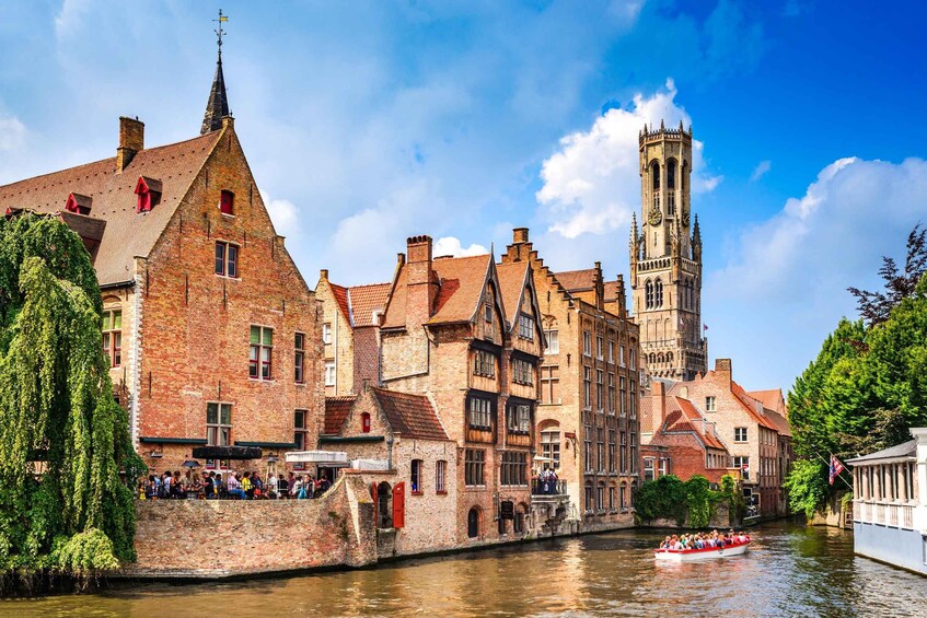Una cittadina europea storica con un fiume, un'alta torre campanaria e una barca piena di turisti. 3