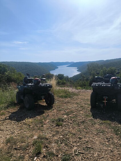 Two ATVs parked on a dirt path overlooking a river. 4