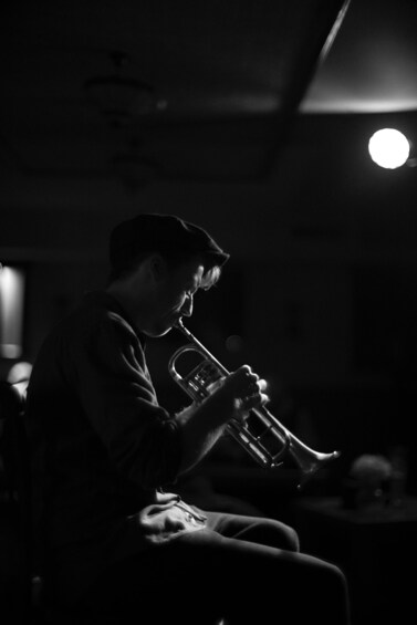 A person playing a trumpet in a dimly lit room. 1