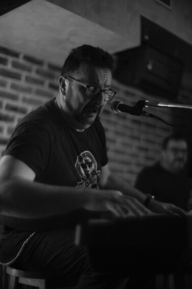 A person playing a keyboard instrument in a dimly lit room with brick walls. 2