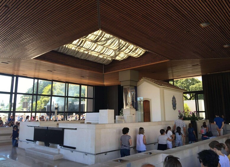 A modern interior with a wooden ceiling, a glass facade, and a central altar. 4
