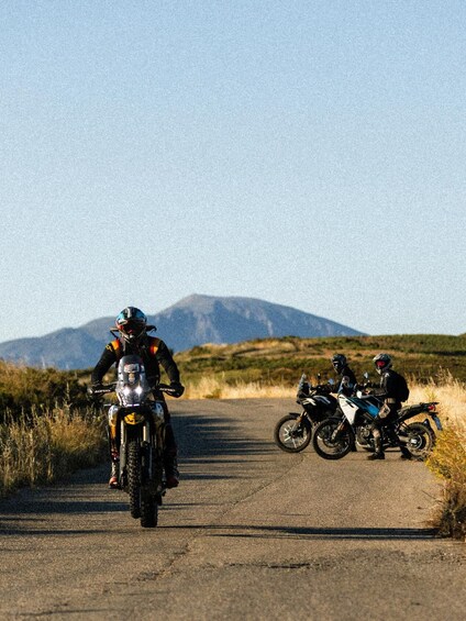 Two motorcyclists on a road with a mountain in the background. 4