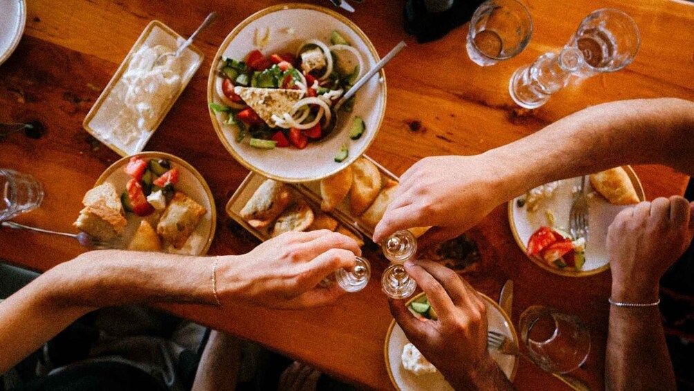 People dining at a wooden table with plates of food and glasses of water. 2