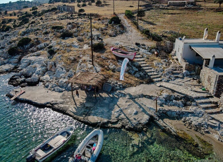 A coastal village with rocky terrain, a thatched-roof hut, boats, and a stone house. 4