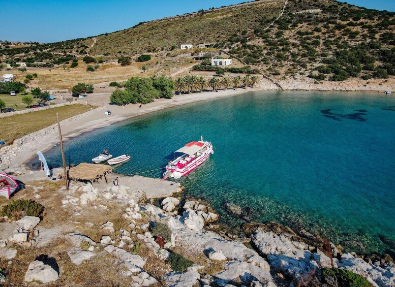 A coastal scene with clear turquoise water, a rocky shoreline, a few boats, and a small white building on a hill. 5