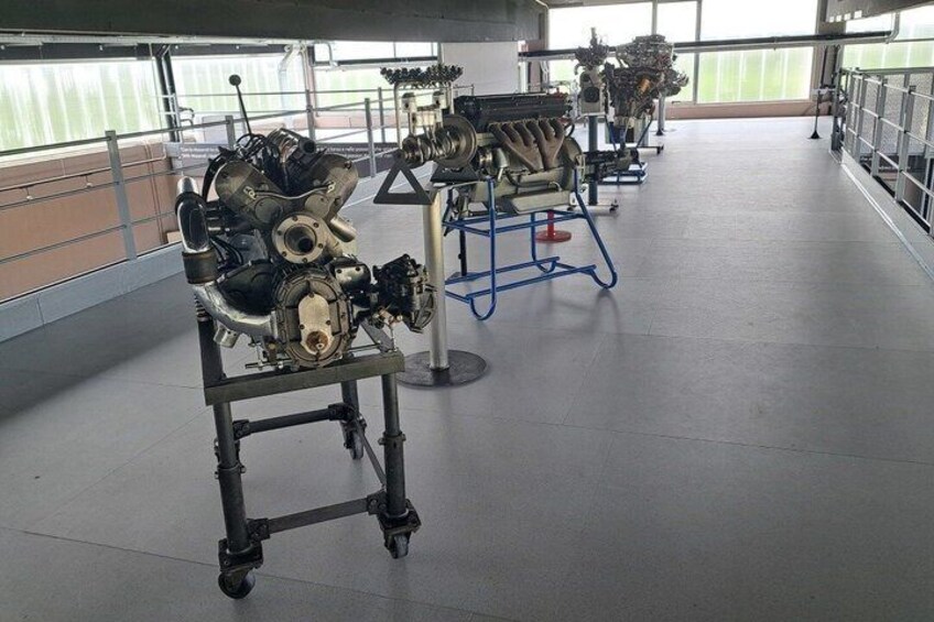 An engine on a stand in a well-lit indoor space with other engines in the background. 2