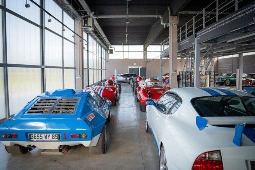 A car showroom with various vintage and modern cars on display. 4