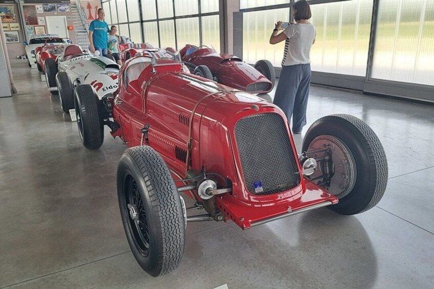 A red vintage car with large tires in a museum. 4