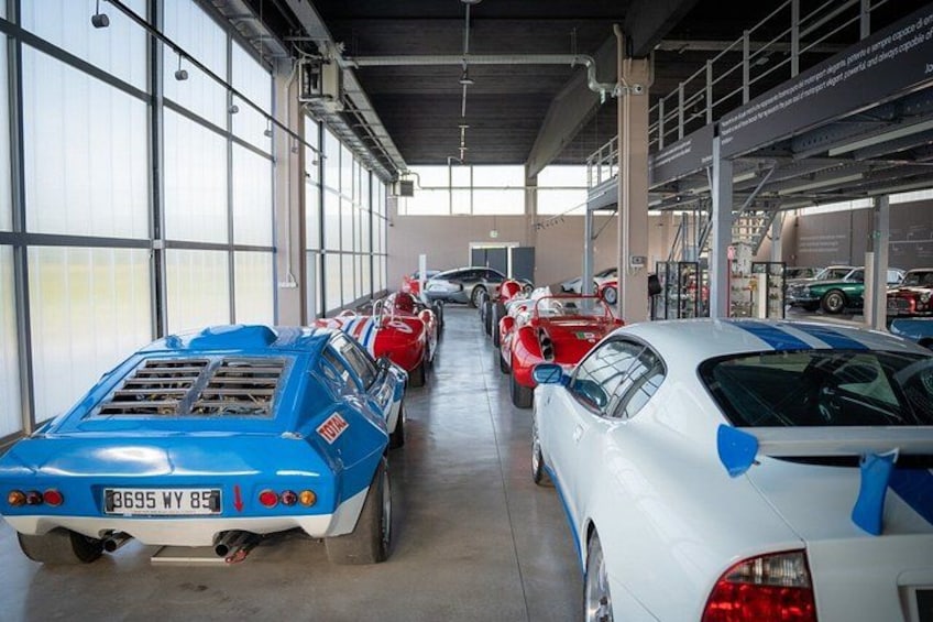 A car showroom with various vintage and modern cars on display. 5