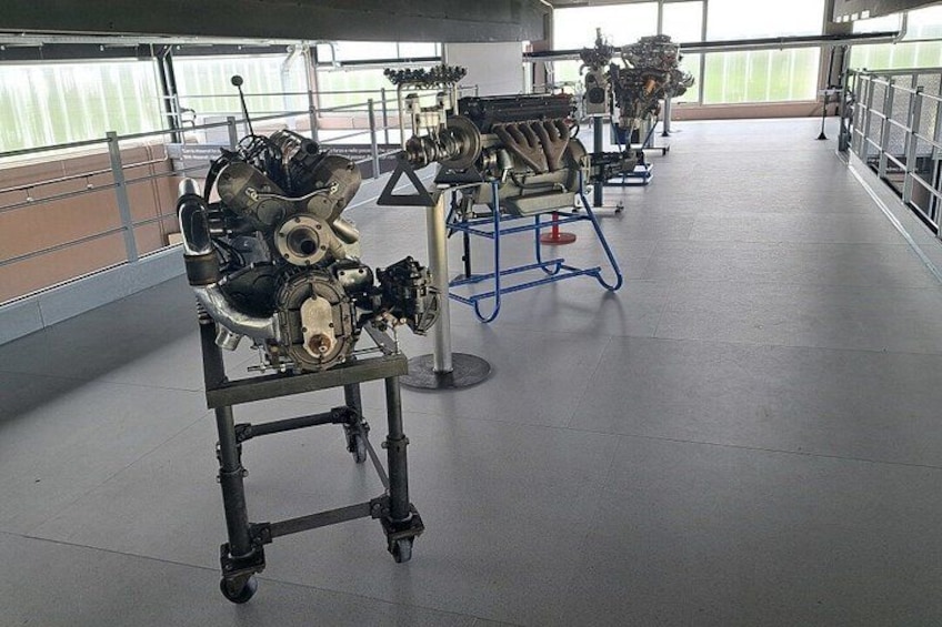 An engine on a stand in a well-lit indoor space with large windows. 3