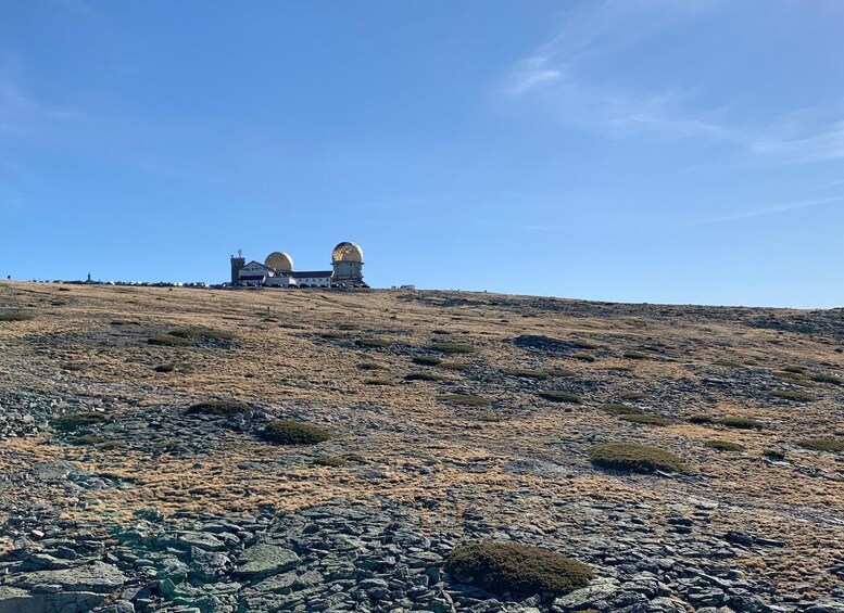 A rocky hill with a building featuring two large domes. 5