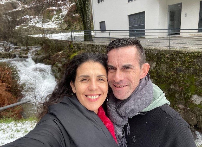 A person taking a selfie with a waterfall and a building in the background. 4