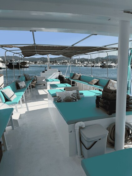 A boat deck with turquoise seating and a view of a marina with boats and hills in the background. 5