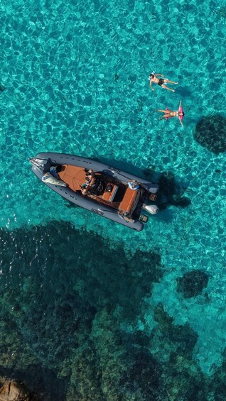 A boat on clear turquoise water with people swimming nearby. 2