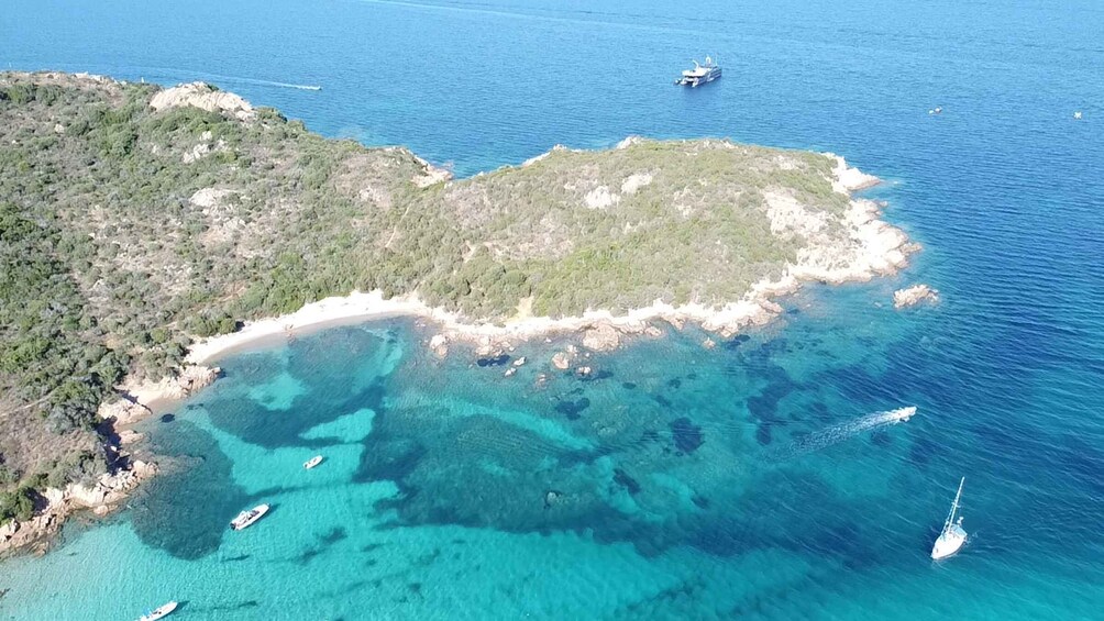 A coastal landscape with clear turquoise waters, a sandy beach, and rocky outcrops. 4