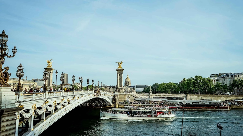 A bridge with ornate statues and a boat on the water. 1