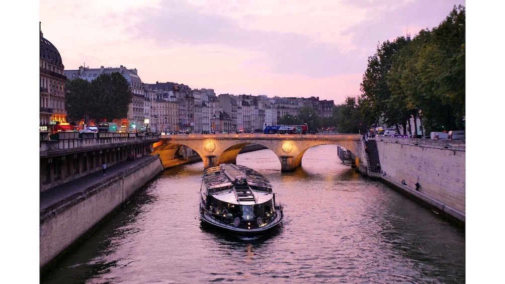 A riverboat on a canal with a bridge in the background. 2